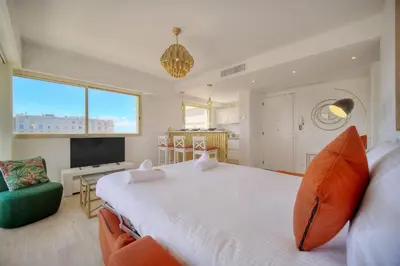 a bedroom with a large white bed and a television at IMMOGROOM - 5 min from the Croisette beaches - Terrace - Ac - Sea view in Cannes