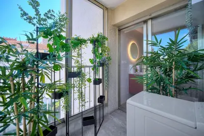 a balcony with plants and a large window at IMMOGROOM - 5 min from the Croisette beaches - Terrace - Ac - Sea view in Cannes