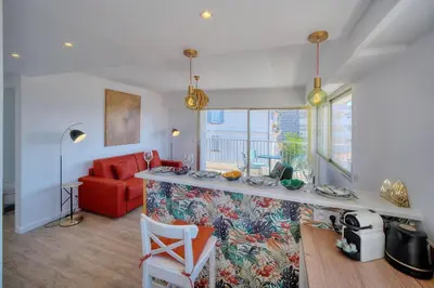 a living room with a red couch and a counter at IMMOGROOM - 5 min from the Croisette beaches - Terrace - Ac - Sea view in Cannes