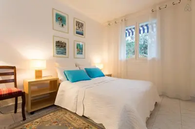 a white bedroom with a large bed with blue pillows at Holiday or Congress, Centre - Beach in Cannes