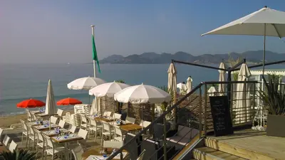 a group of tables and chairs with umbrellas on the beach at Holiday or Congress, Centre - Beach in Cannes