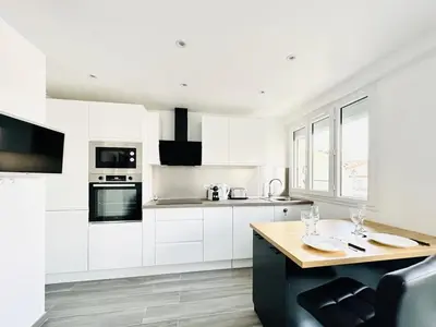 a kitchen with white cabinets and a wooden table at Le Royal Carnot - Studio - Cannes Centre Terrasse in Cannes