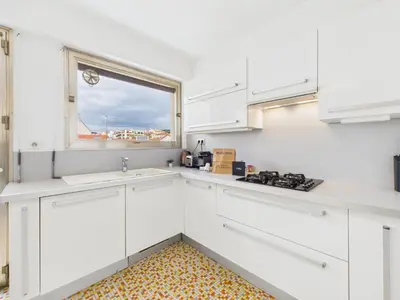 a kitchen with white cabinets and a window at Central -300m Palais- Seaview-A/C-WIFI-spacieux in Cannes