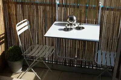 a bathroom with a sink and a chair next to a fence at Studio charmant au cœur de Cannes avec balcon et parking in Cannes