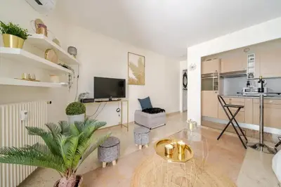 a living room with a table and a kitchen at Studio charmant au cœur de Cannes avec balcon et parking in Cannes