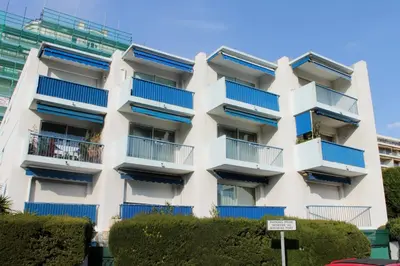 a white apartment building with blue balconies at Studio charmant au cœur de Cannes avec balcon et parking in Cannes