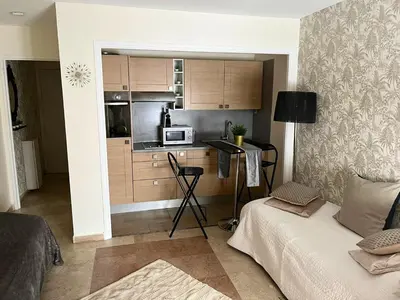 a room with a kitchen with a couch and a microwave at Studio charmant au cœur de Cannes avec balcon et parking in Cannes