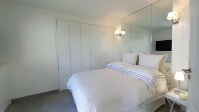 a white bedroom with a bed and a mirror at Bella Park in Cannes