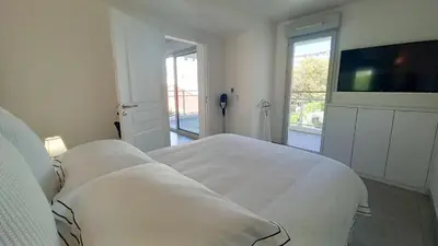 a white bedroom with a bed and a flat screen tv at Bella Park in Cannes