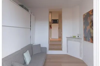 a living room with a gray couch and a hallway at Un Écrin au Suquet - Studio, clim, balcon, plage, Palais des Festivals in Cannes