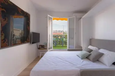 a bedroom with a large white bed and a window at Un Écrin au Suquet - Studio, clim, balcon, plage, Palais des Festivals in Cannes