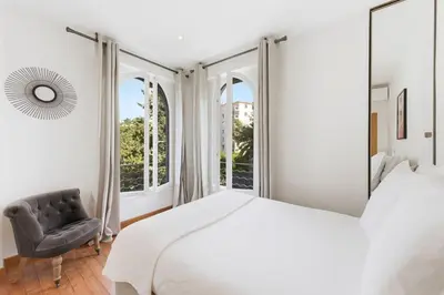 a white bedroom with a large bed and a chair at Cozy 1 bedroom flat,free parking, close to center in Cannes