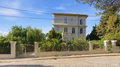 a white house behind a fence at Cozy 1 bedroom flat,free parking, close to center in Cannes