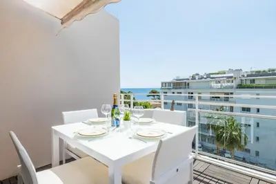 a white dining room with a view of the ocean at 3-Room Luxury Apartment with Pool and Sea View Steps from the Beach in Cannes