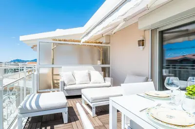a balcony with white furniture and a table and chairs at 3-Room Luxury Apartment with Pool and Sea View Steps from the Beach in Cannes