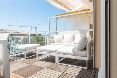 a balcony with a white couch and two chairs at 3-Room Luxury Apartment with Pool and Sea View Steps from the Beach in Cannes