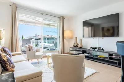 a living room with a couch and a tv at 3-Room Luxury Apartment with Pool and Sea View Steps from the Beach in Cannes