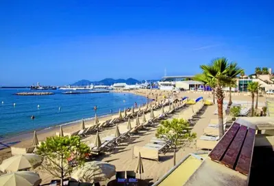a beach with chairs and umbrellas and the ocean at CANNES t4 bourgeois 790M de la plage, Palais et Croisette in Cannes