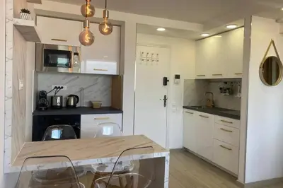 a kitchen with white cabinets and a table and chairs at Vue panoramique, plage à 100m in Cannes