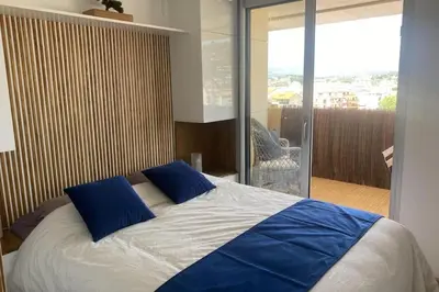 a bedroom with a bed with blue pillows and a balcony at Vue panoramique, plage à 100m in Cannes