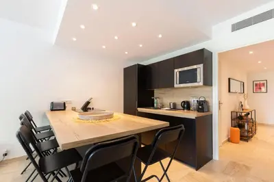 a kitchen with a large wooden table and black cabinets at WE CANNES ! Exceptional 4 rooms apartment Cannes Center swimming pool in Cannes
