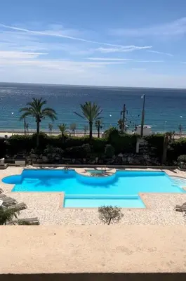 a blue swimming pool with the ocean in the background at Appartement vue sur mer in Cannes