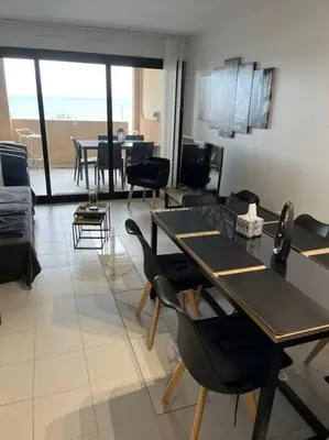 a living room with a couch and a table and chairs at Appartement vue sur mer in Cannes