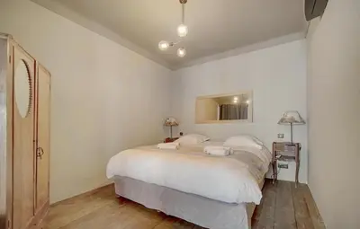 a white bedroom with a large bed and a table at Red & Bleue YourHostHelper in Cannes