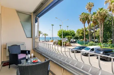 a balcony with a view of the beach and cars at Les 3 Palmiers YourHostHelper in Cannes