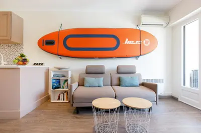 a living room with a couch and a surfboard on the wall at Les 3 Palmiers YourHostHelper in Cannes