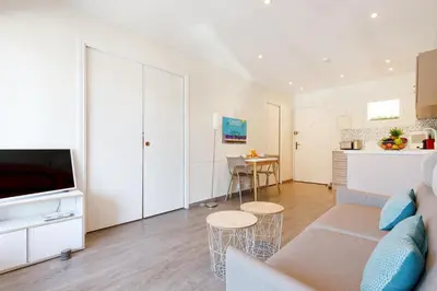 a living room with a couch and a kitchen at Les 3 Palmiers YourHostHelper in Cannes