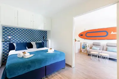 a bedroom with a bed with a surfboard on the wall at Les 3 Palmiers YourHostHelper in Cannes