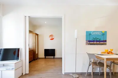 a living room with a dining room table and a mirror at Les 3 Palmiers YourHostHelper in Cannes