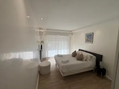 a white bedroom with a bed and a window at Mathéo in Cannes
