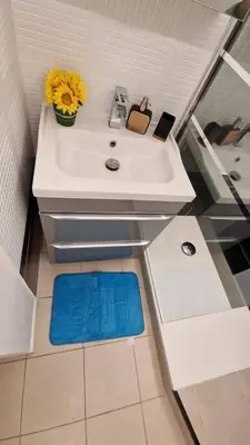 a bathroom with a white sink with a blue mat at magnifique APPARTEMENT vue mer Parking Piscine Plage Climatisé in Cannes