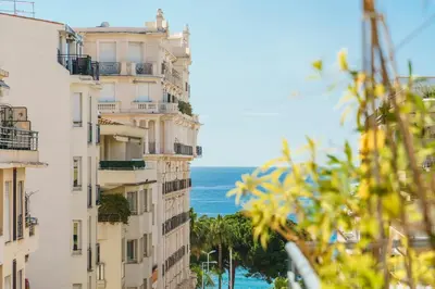 a view of two buildings with the ocean in the background at Downtown Cannes Modern 1-Br Apartment in Cannes