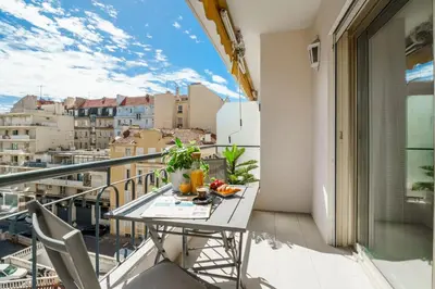 a table on a balcony with a view of a city at Downtown Cannes Modern 1-Br Apartment in Cannes