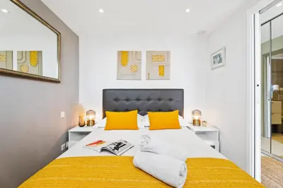 a bedroom with a large bed with yellow pillows at Downtown Cannes Modern 1-Br Apartment in Cannes