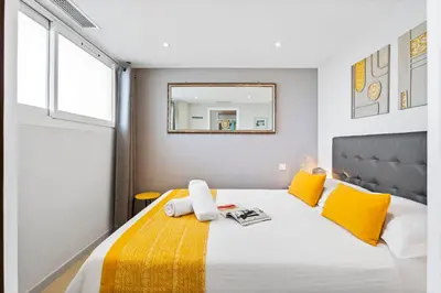 a bedroom with a bed with yellow pillows and a mirror at Downtown Cannes Modern 1-Br Apartment in Cannes
