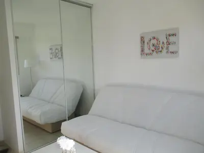 a living room with a white couch and a mirror at Studio au calme à 5mn de la mer et de toutes attractions de la ville in Cannes