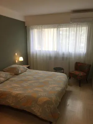 a bedroom with a bed and a chair and a window at Appartement Mimosa Croisette in Cannes