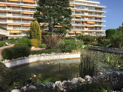a pond in front of a large apartment building at Appartement Mimosa Croisette in Cannes
