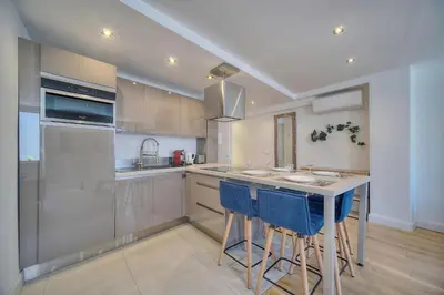 a kitchen with a island with blue bar stools at IMMOGROOM - Heart of the Suquet - City center - Modern in Cannes