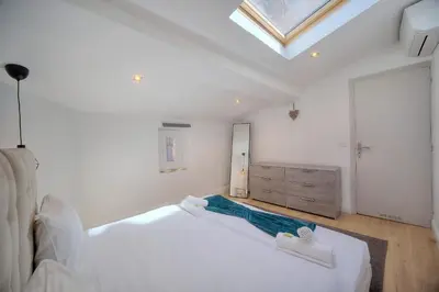 a bedroom with a large white bed and a skylight at IMMOGROOM - Heart of the Suquet - City center - Modern in Cannes