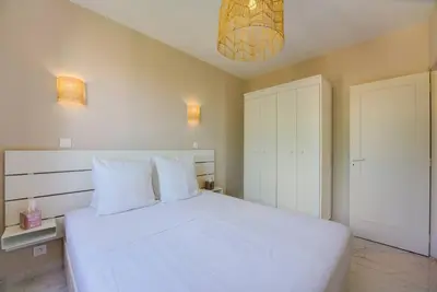 a bedroom with a large white bed and a chandelier at Cannes Californie Beautiful Apt with Sea View in Cannes