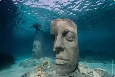 a statue of heads and a diver in the water at 06DI Cannes Hoche in Cannes