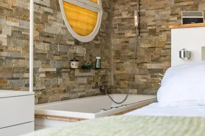 a bathroom with a tub and a bed and a mirror at Penthouse Duplex with Rooftop Terrace in Cannes