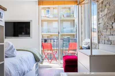 a bedroom with a bed and a balcony with red chairs at Penthouse Duplex with Rooftop Terrace in Cannes