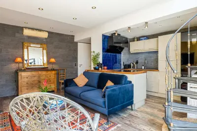 a living room with a blue couch and a kitchen at Penthouse Duplex with Rooftop Terrace in Cannes