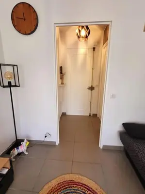 a hallway with a clock on the wall and a door at Cosy Studio à Cannes 8 min de la Croisette in Cannes